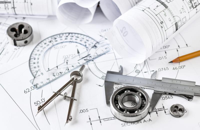 Engineering blueprint with drafting tools, caliper, protractor, and mechanical component