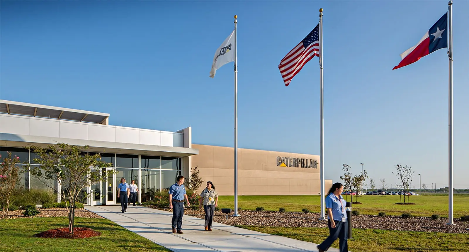 People walking outside a Caterpillar campus building with flags